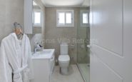 Modern Cyprus Villa Rent, organized bathroom with sleek fixtures, glass shower, and luxurious bathrobe detail.