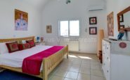 Cyprus Villa Rent with Serenely decorated bedroom with red accents, white bedding, and artistic decor for relaxation.