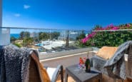 Luxurious coastal balcony in Cyprus Villa for Rent with champagne, sea view, and vibrant flowers.