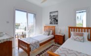 A serene and well-lit bedroom with two single beds, nightstand, and balcony view in Cyprus Villa Rent