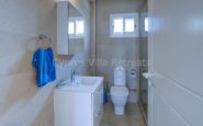 Cyprus Villa Rent - Modern and minimalist bathroom with blue towel, white sink, mirror cabinet, and toilet.