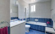 Cyprus Villa Rent with Modern blue and white bathroom with bathtub, flowers, and natural light.