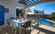 Luxurious Mediterranean Cyprus Villa for Rent with patio with dining area, pool, and lush greenery.