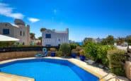 Luxurious coastal Cyprus Villa Rent with pool and sun lounger, set against blue sky and sea.