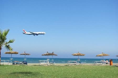 Tranquil beach scene with airplane near Larnaca airport.