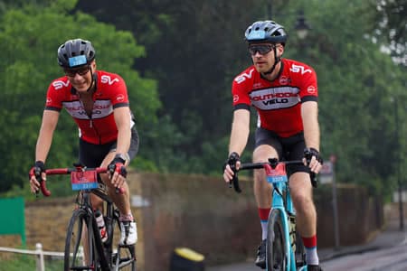 Two cyclists in matching outfits enjoying a leisurely ride on a smooth road.