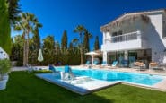 Luxurious modern villa in Paphos Cyprus with pool and palm trees against clear blue sky for relaxing holidays.