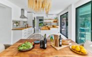 Modern kitchen and dining area with rustic table setting and outdoor patio view.