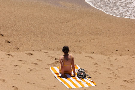 Solitary individual in yellow bikini relaxing on striped beach towel by Polis Chrysochous Beach